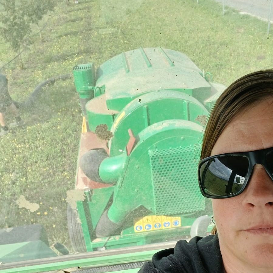 Person im Traktor mit Sonnenbrille, Blick nach vorne in die Landschaft.